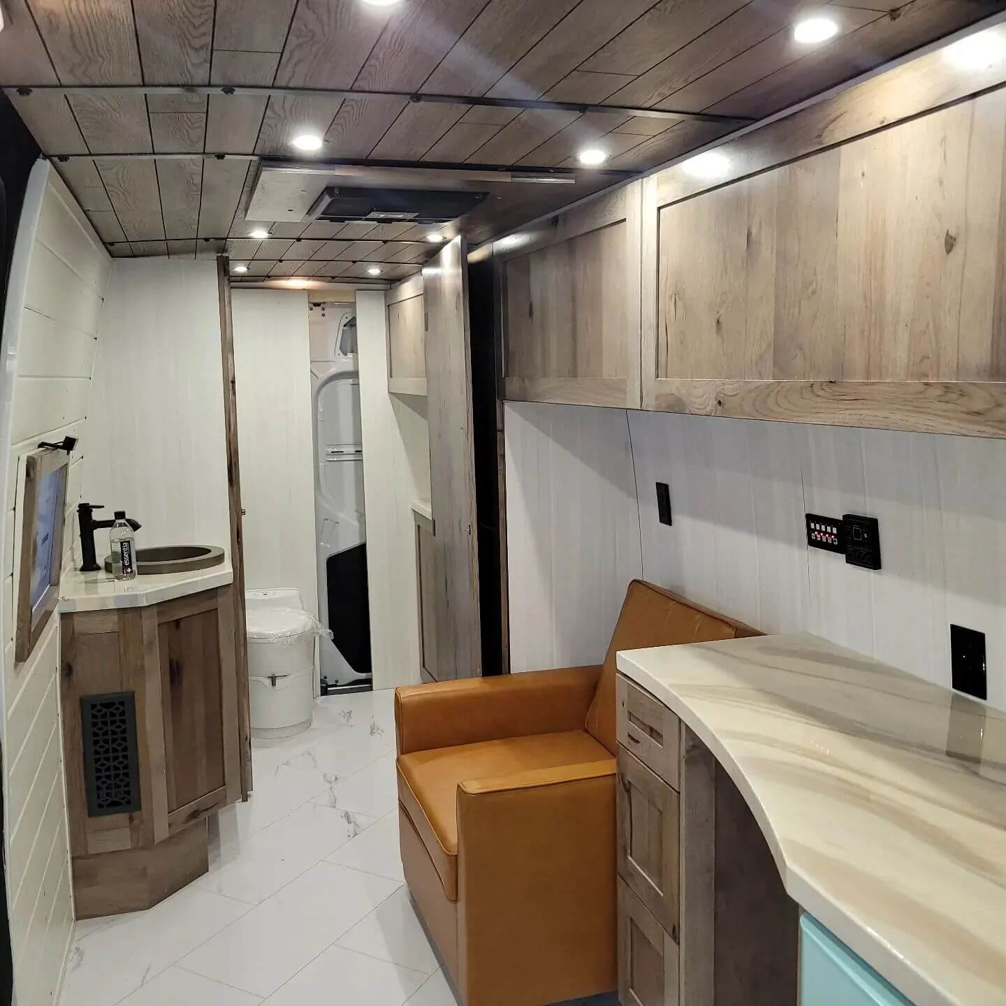 A finished RV interior remodel with wood cabinetry, stone countertops, and recessed lighting