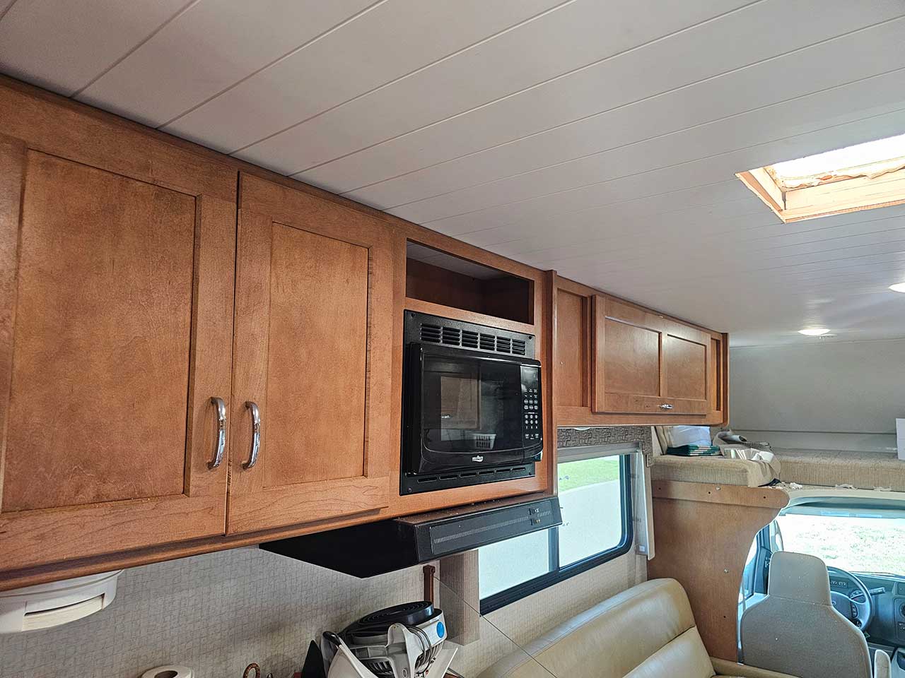 New overhead cabinetry and a wood-plank ceiling installed in an RV interior